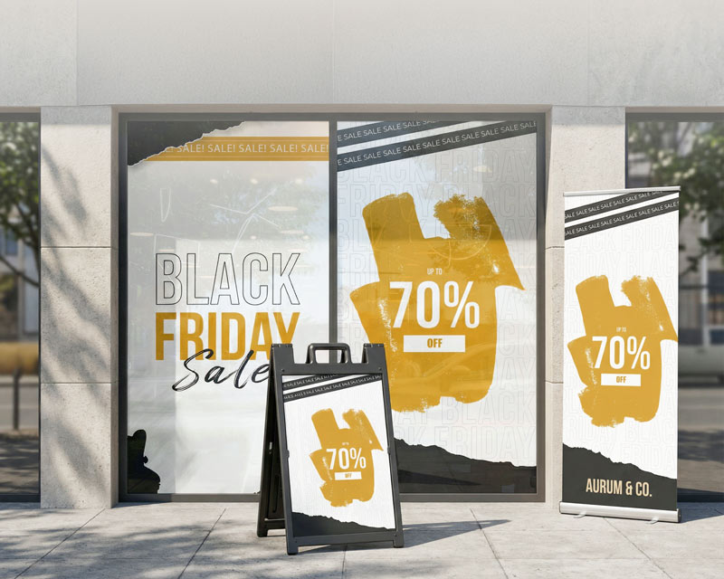 Retail store promotional signage, including window graphics, a sidewalk display, and a banner