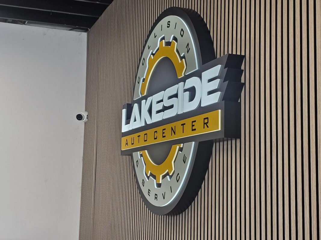 Professional illuminated 3D business sign for an auto center and collision service mounted on a slat wall