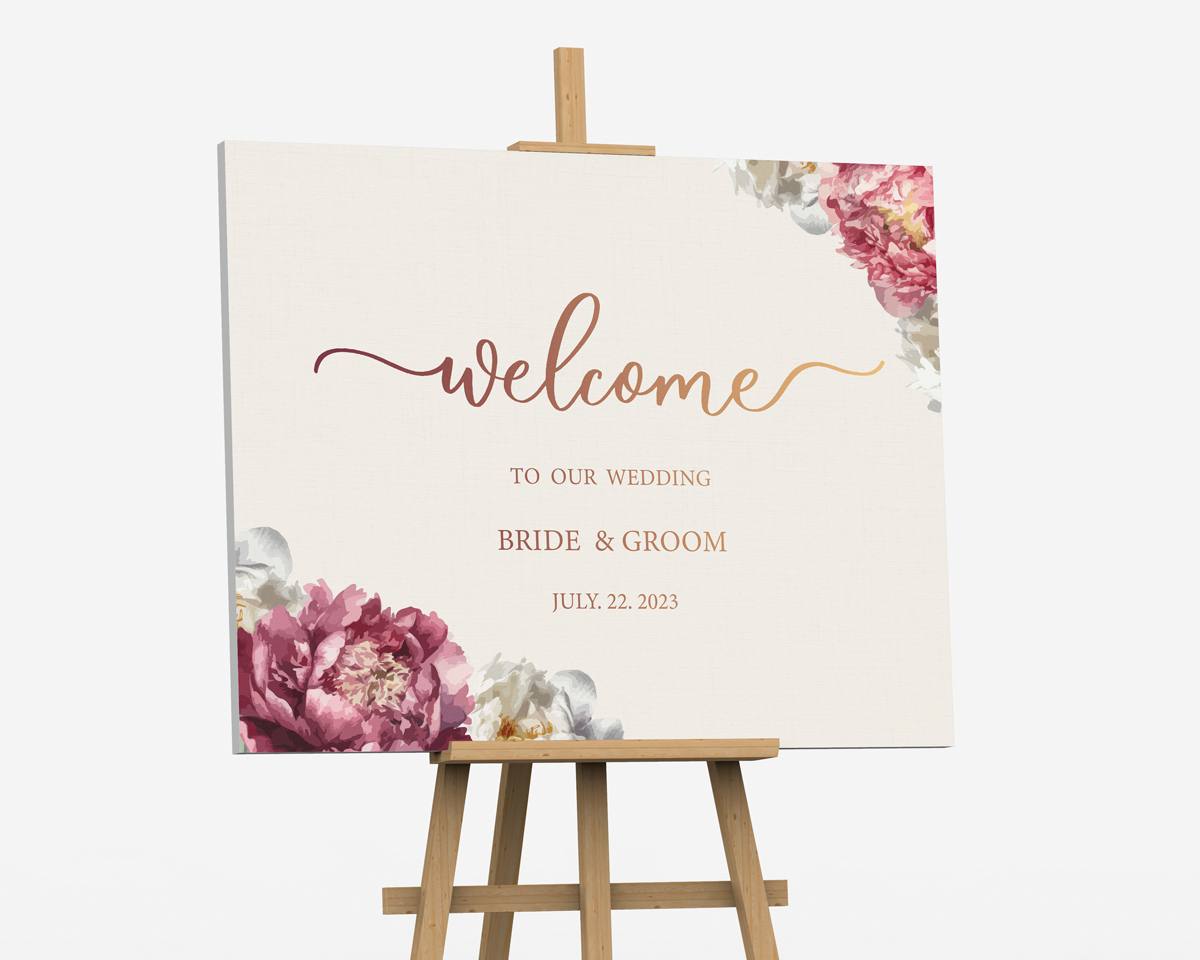 Wedding welcome foam board with pink flowers displayed on a wooden easel.