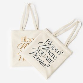 Two cream tote bags with decorative lettering displayed flat.