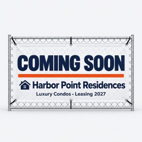 White mesh fence banner reading Coming Soon zip-tied to a chain-link construction fence